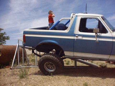 1988 Ford Bronco - A modified Ford Bronco is parked outdoors with a young boy standing in the cargo area.