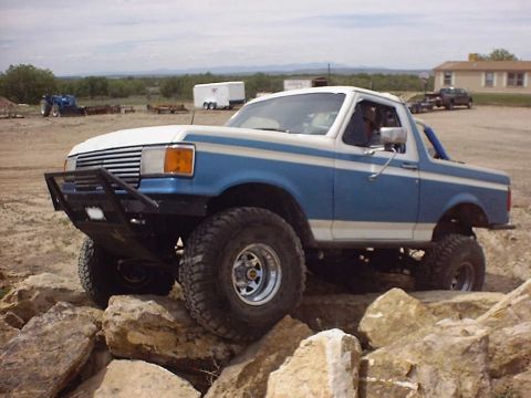 1988 Ford Bronco - Modified Ford Bronco navigating a rocky trail during an off-road event.