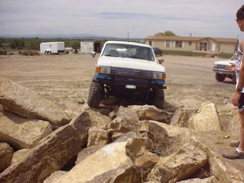 1988 Ford Bronco - A white 1984 Toyota 4Runner navigates a challenging rocky terrain, with another vehicle visible in the background.
