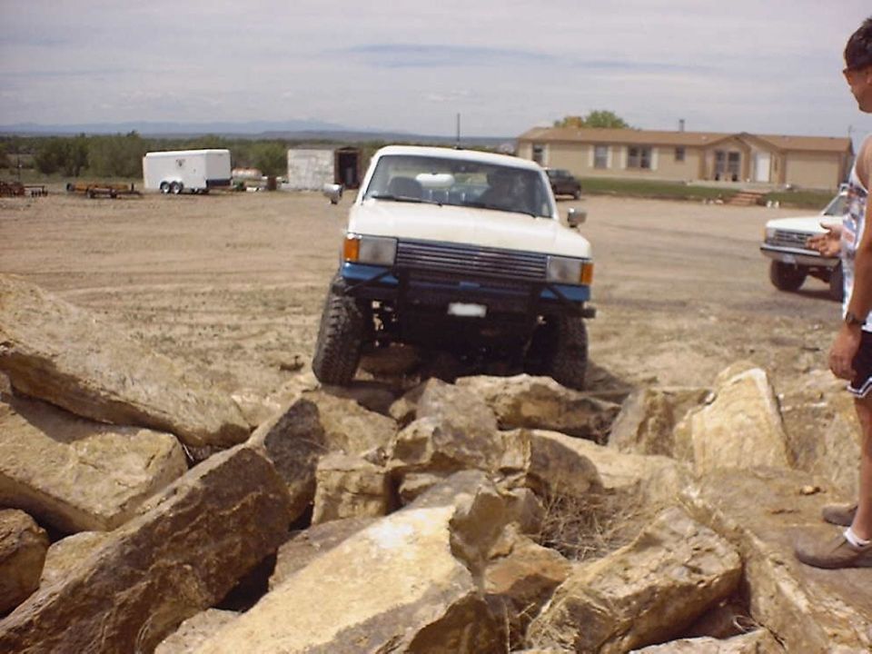 White 1984 Toyota 4Runner with blue bumper climbing over large rocks