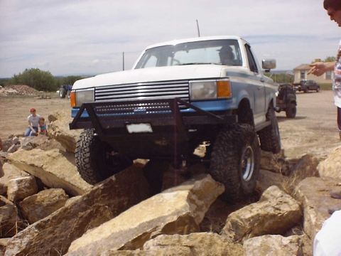 1988 Ford Bronco - This lifted pickup truck is shown off-roading over a rocky terrain.