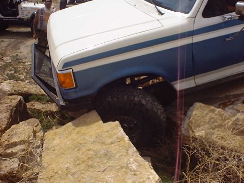 1988 Ford Bronco - A two-tone Ford Bronco navigates a rocky obstacle course, with a Jeep visible in the background.