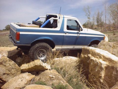 1988 Ford Bronco - This modified Ford Bronco is shown tackling a rocky trail, demonstrating its off-road capabilities.