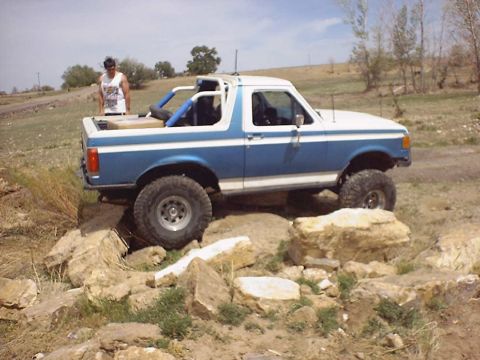 1988 Ford Bronco - Modified Ford Bronco tackling a challenging off-road course with large rocks.
