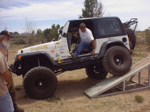 1988 Ford Bronco - A Jeep Wrangler is positioned on a ramp, with a person entering the vehicle from the open door.