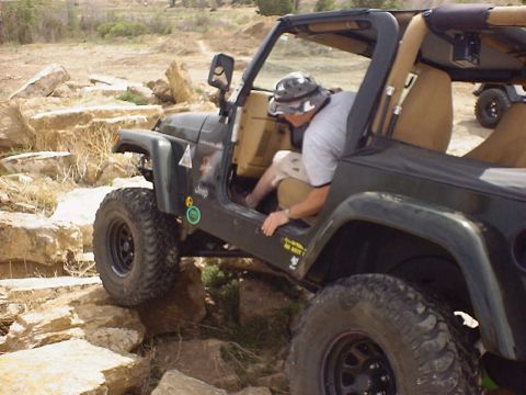 1988 Ford Bronco - A Jeep Wrangler navigates a rocky trail with a driver entering the vehicle.