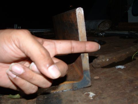 1979 Ford Bronco - A finger indicates a section of a metal angle bracket on a cluttered surface, with a website watermark visible.