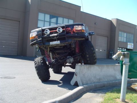 1993 Ford Bronco - This heavily modified 1992 Ford Bronco is shown with its front tires on a concrete barrier, highlighting its off-road capabilities.