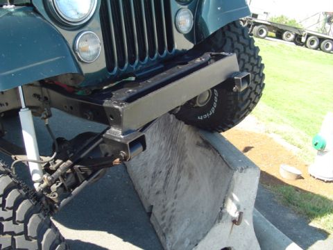 1993 Ford Bronco - Front view of a green Jeep with an aftermarket bumper and large tires, positioned on a concrete barrier.
