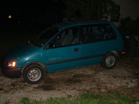 1979 Ford Bronco - A teal minivan is parked on a dirt lot at night, with 'SUMMIT GL' visible on its side.