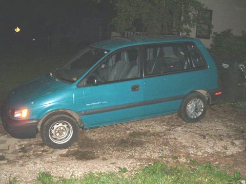 1979 Ford Bronco - A teal minivan is parked outdoors at night on a gravel surface.