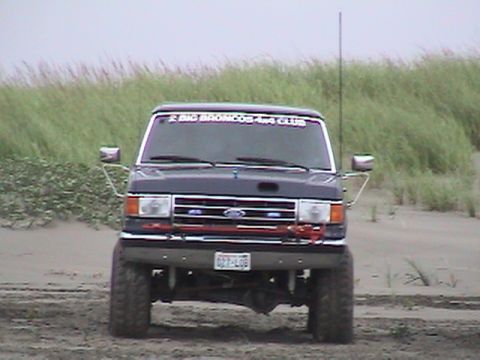 1994 Ford Explorer - This Ford F-Series truck has a "BIG BRONCOS 4x4 CLUB" sticker on its windshield and is parked on a sandy area with grass in the background.