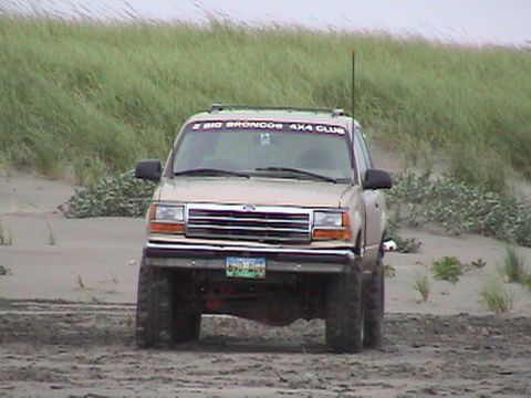 1994 Ford Explorer - A tan Ford Explorer is parked on a sandy terrain with tall grass in the background.