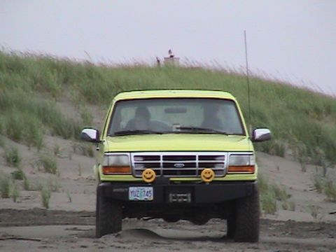 1994 Ford Explorer - Front view of a yellow 1994 Ford Explorer with custom smiley face fog lights on a sandy beach.