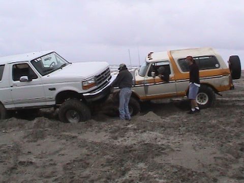 1994 Ford Explorer - Two Ford Broncos are stuck in the sand, with two men standing near them.