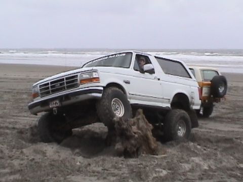 1994 Ford Explorer - White 1994 Ford Bronco navigating sandy terrain on a beach with a second vehicle visible.