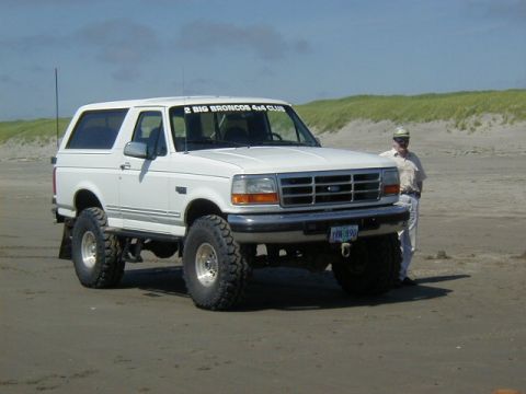 1994 Ford Explorer - White 1994 Ford Bronco on a sandy beach, modified with large off-road tires.