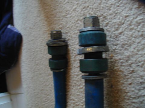 1988 Ford Bronco - Two blue suspension bushings with metal hardware are shown close up against a carpeted background.