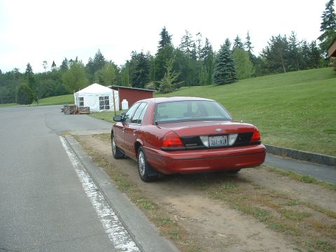 1999 Ford Crown Victoria - Rear view of a red 1998 Ford Crown Victoria parked on a dirt path.