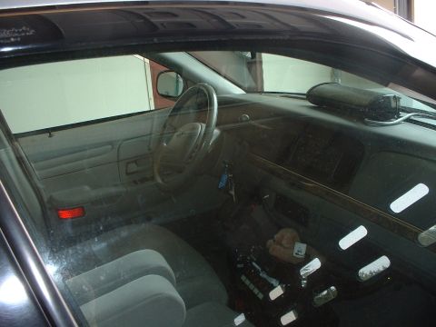 1999 Ford Crown Victoria - The interior of a 1999 Ford Crown Victoria police car, a dashboard, steering wheel, and seating.