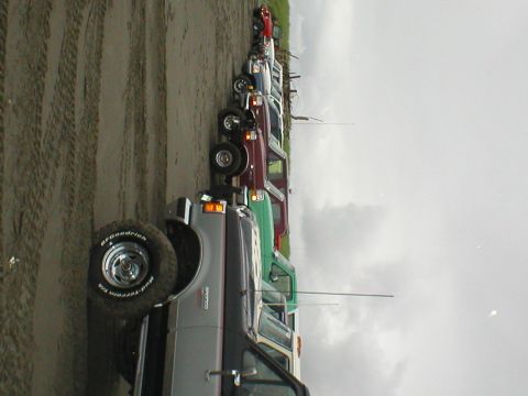 1978 Ford Bronco - A line of SUVs and trucks are parked on a sandy beach, with a 1978 Ford Bronco in the foreground.