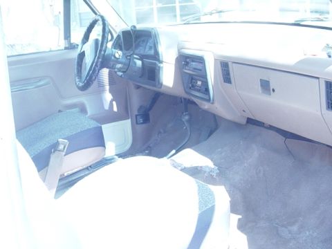 1989 Ford Bronco - The interior of the vehicle shows the dashboard, steering wheel, and part of the passenger seat.
