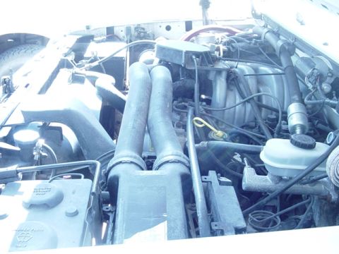 1989 Ford Bronco - The engine bay of a white Ford Bronco, likely from the 1990 model year, is shown in this close-up view.