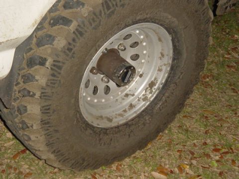 1989 Ford Bronco - This image shows a close-up of a muddy off-road tire mounted on a silver alloy wheel, a chrome hub. The registry claims it is a 1989 Ford B…