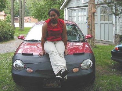 1997 Ford Taurus - A 1997 Ford Taurus is seen from the front, partially covered by a black bra, with a person seated on its hood.