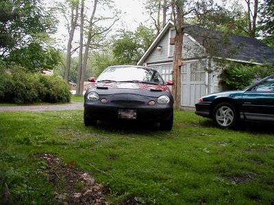 1997 Ford Taurus - Two cars are parked in a yard near a garage; one is a 1997 Ford Taurus.