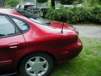 1997 Ford Taurus - The rear quarter panel of a red sedan is visible, with a second vehicle in the background.