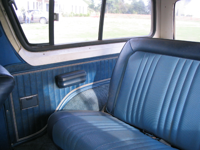 Blue vinyl bench seat and door panel interior of a vehicle with window view
