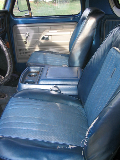 1978 Ford Bronco - The interior of this classic SUV features blue vinyl and cloth seats with a center console and cup holders.
