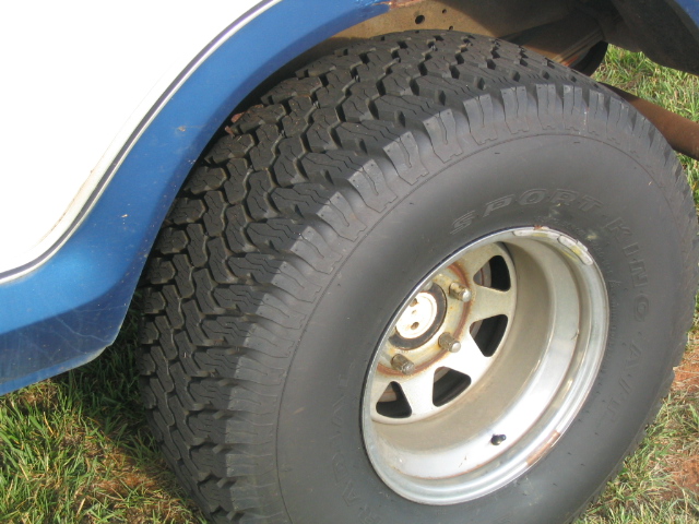 White and blue vehicle's rear tire and wheel well with a chrome rim