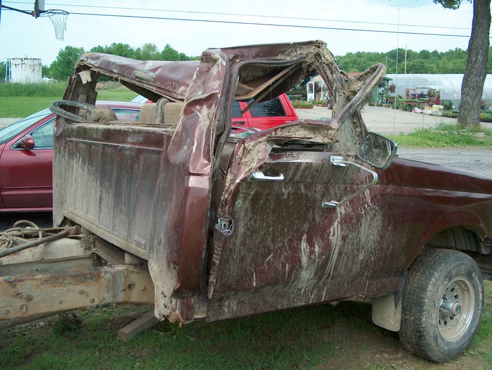 Totaled maroon 1990 Ford F-150 pickup truck, 3q-front view, heavily damaged cab and roof