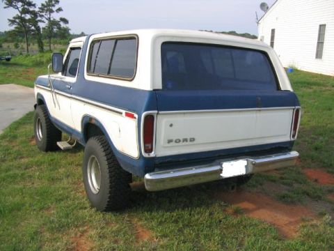 1978 Ford Bronco - Rear view of a 1978 Ford Bronco parked on grass with a white house in the background.