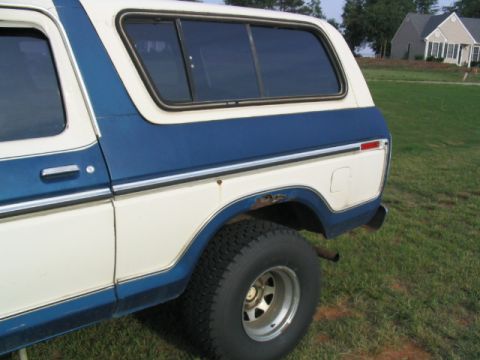 1978 Ford Bronco - The side profile of a classic Ford Bronco shows its two-tone paint scheme and a portion of the rear tire.
