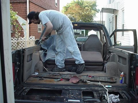 1993 Ford Bronco - A person works on the interior of a 1992 Ford Bronco, with the tailgate open.