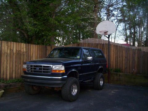1994 Ford Bronco - Dark blue 1994 Ford Bronco with lifted suspension sits in a driveway.