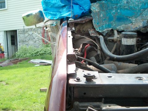 1990 Ford F-150 - The engine bay of a vehicle is partially covered by a blue tarp, with visible hoses and wiring.