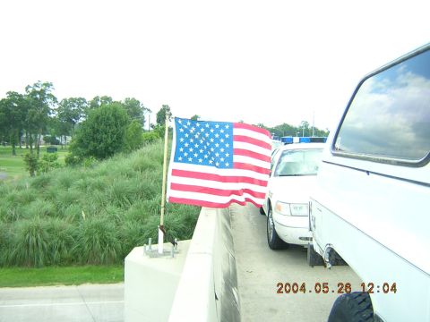 1984 Chevrolet Blazer - An American flag waves next to a line of white vehicles, one appearing to be a police car.