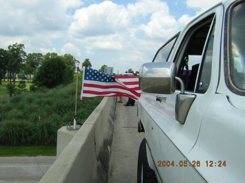1984 Chevrolet Blazer - An American flag waves from the side of a white vehicle on a sunny day.
