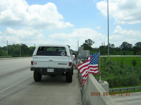 1984 Chevrolet Blazer - A white Chevrolet SUV is parked on the side of a highway, adorned with American flags.