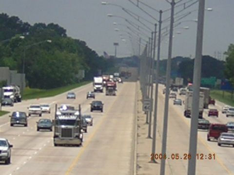 1984 Chevrolet Blazer - A busy highway scene with multiple vehicles traveling in both directions under a cloudy sky.