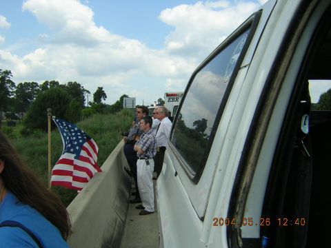 1984 Chevrolet Blazer - People observe from a highway overpass, with an American flag waving and a vehicle in the foreground.