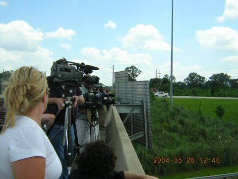 1984 Chevrolet Blazer - A media crew is positioned on an overpass, filming a white pickup truck driving on the road below.