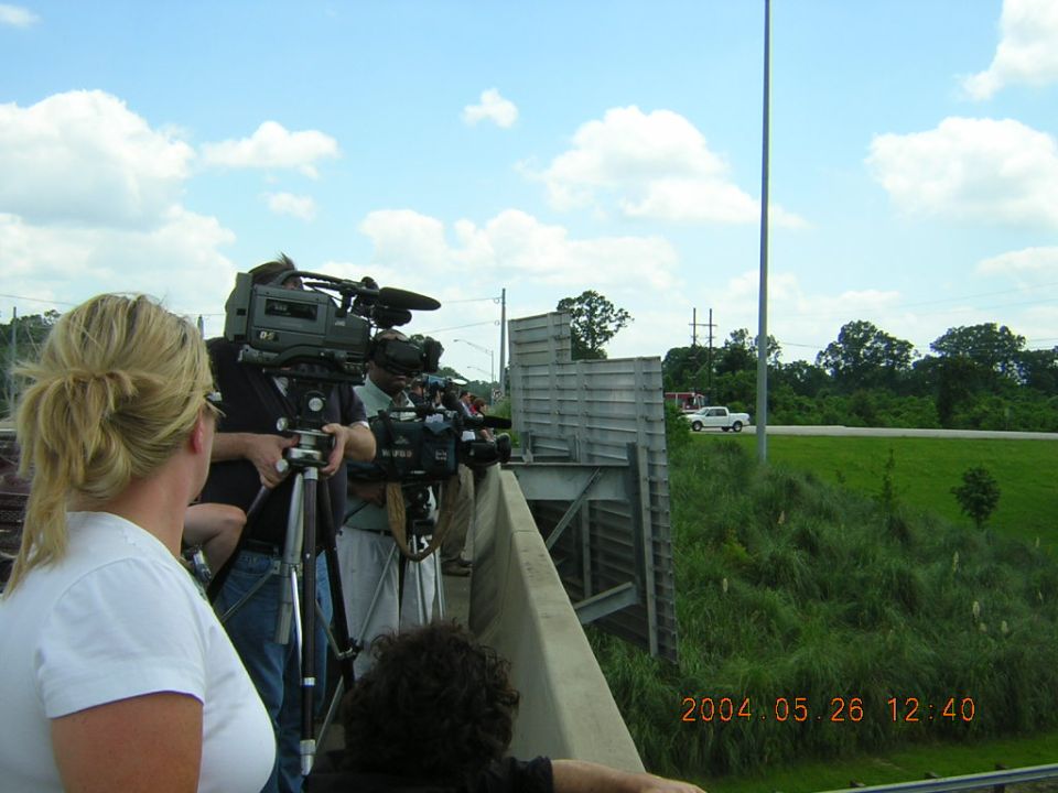 Media filming a white pickup truck from an overpass. Date stamp shows 2004