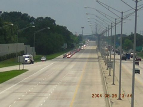 1984 Chevrolet Blazer - A long line of vehicles travels down a highway, likely part of a funeral procession.