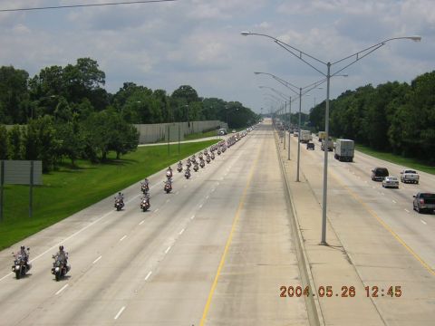 1984 Chevrolet Blazer - A large group of motorcycles travels in formation on a multi-lane highway under a cloudy sky.