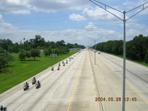 1984 Chevrolet Blazer - A long line of motorcycles travels down a multi-lane highway under a cloudy sky.